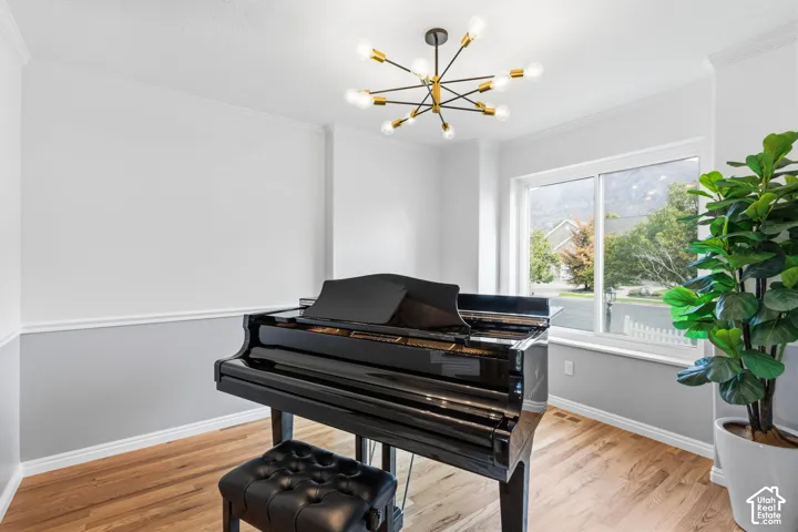 Mid-century modern-inspired multi-arm chandelier with brushed gold accents, wood-finish flooring, two-tone wall treatment with chair rail molding, and a sliding glass window