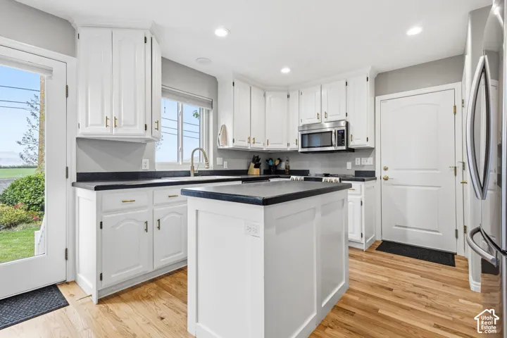 Kitchen featuring white cabinetry, center island, dark countertops, wood-finish flooring, and recessed lighting