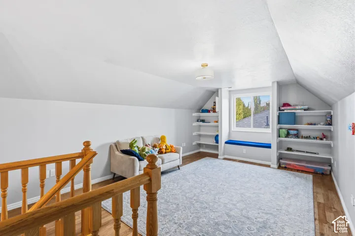 Wood-finish flooring, vaulted ceilings, built-in shelving, integrated window seat, and wood staircase railing