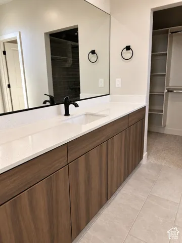 Flat-panel wood-finish cabinetry featuring a light-toned solid surface countertop, rectangular undermount sink, matte black faucet, and full-width vanity mirror