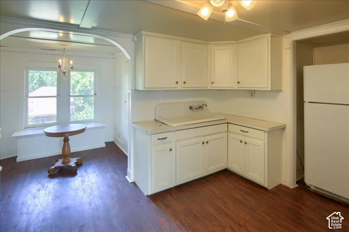 Kitchen featuring white cabinetry with dark hardware, a corner sink basin, and wood-finish flooring