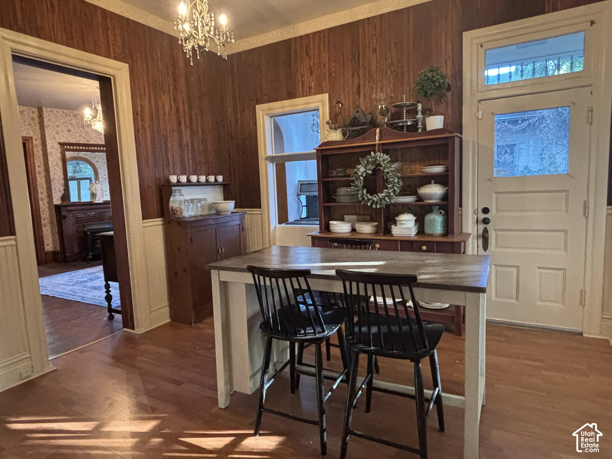 Wood-paneled wall accents, painted wainscoting, ornamental chandelier, and exterior-facing door with transom window