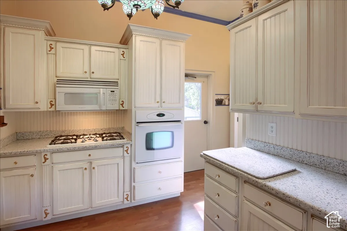 Kitchen featuring white beadboard cabinetry, white built-in appliances, a gas cooktop, and speckled light-colored countertops