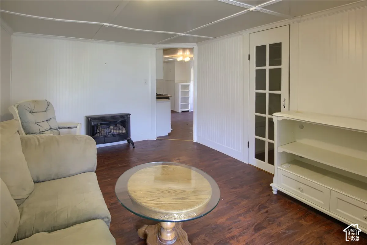 Wood-finish flooring, white beadboard accent wall, freestanding electric fireplace, and a glass-paneled interior door