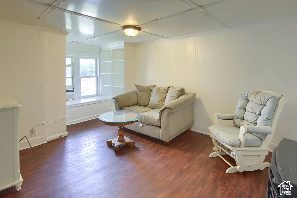 Wood-finish flooring, white beadboard wall paneling, built-in shelving, and a window with a deep sill