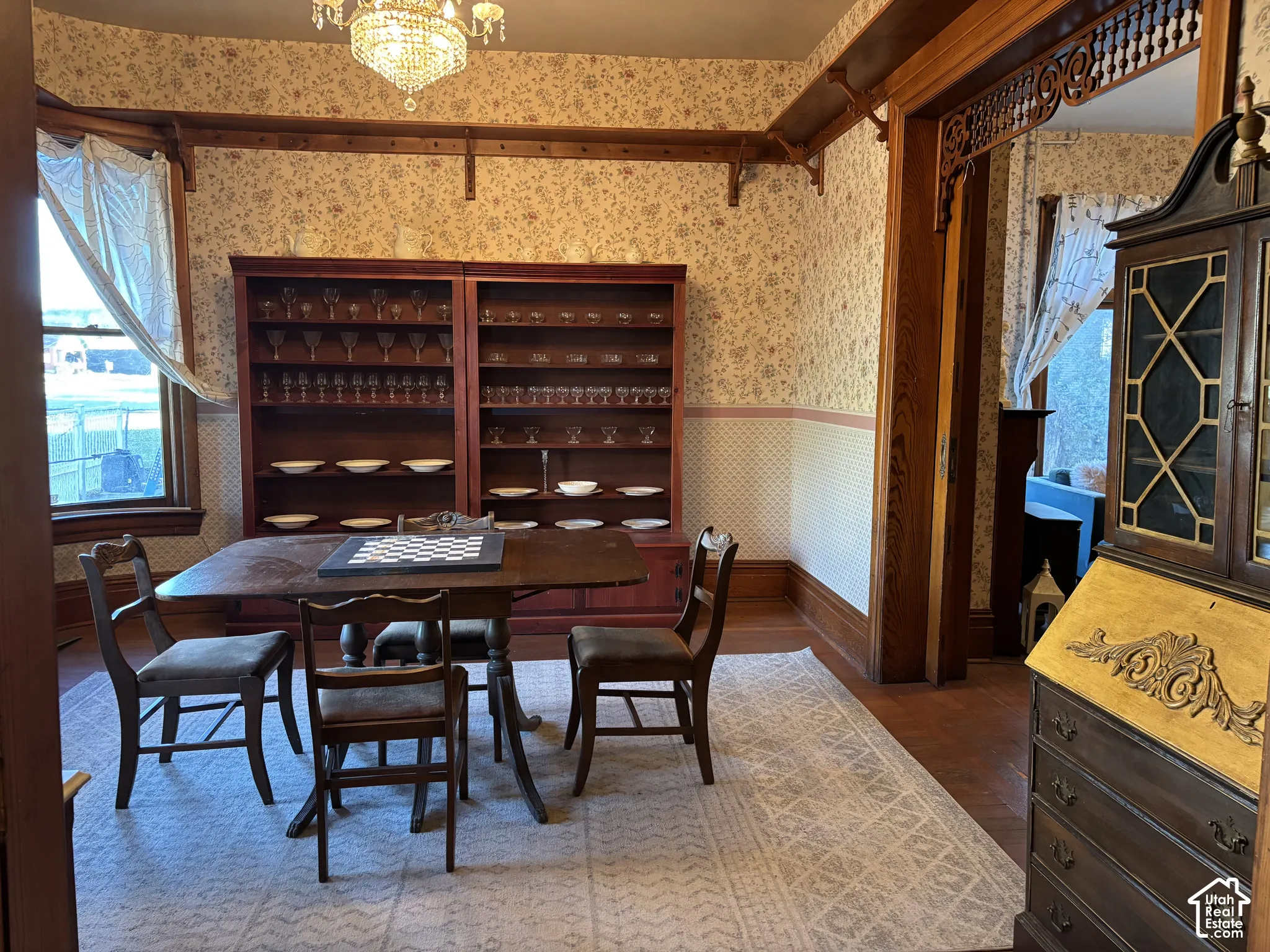 Dining space featuring built-in wood cabinetry with shelving, intricate wooden door framing, period-style decorative trim, and a multi-tiered crystal chandelier