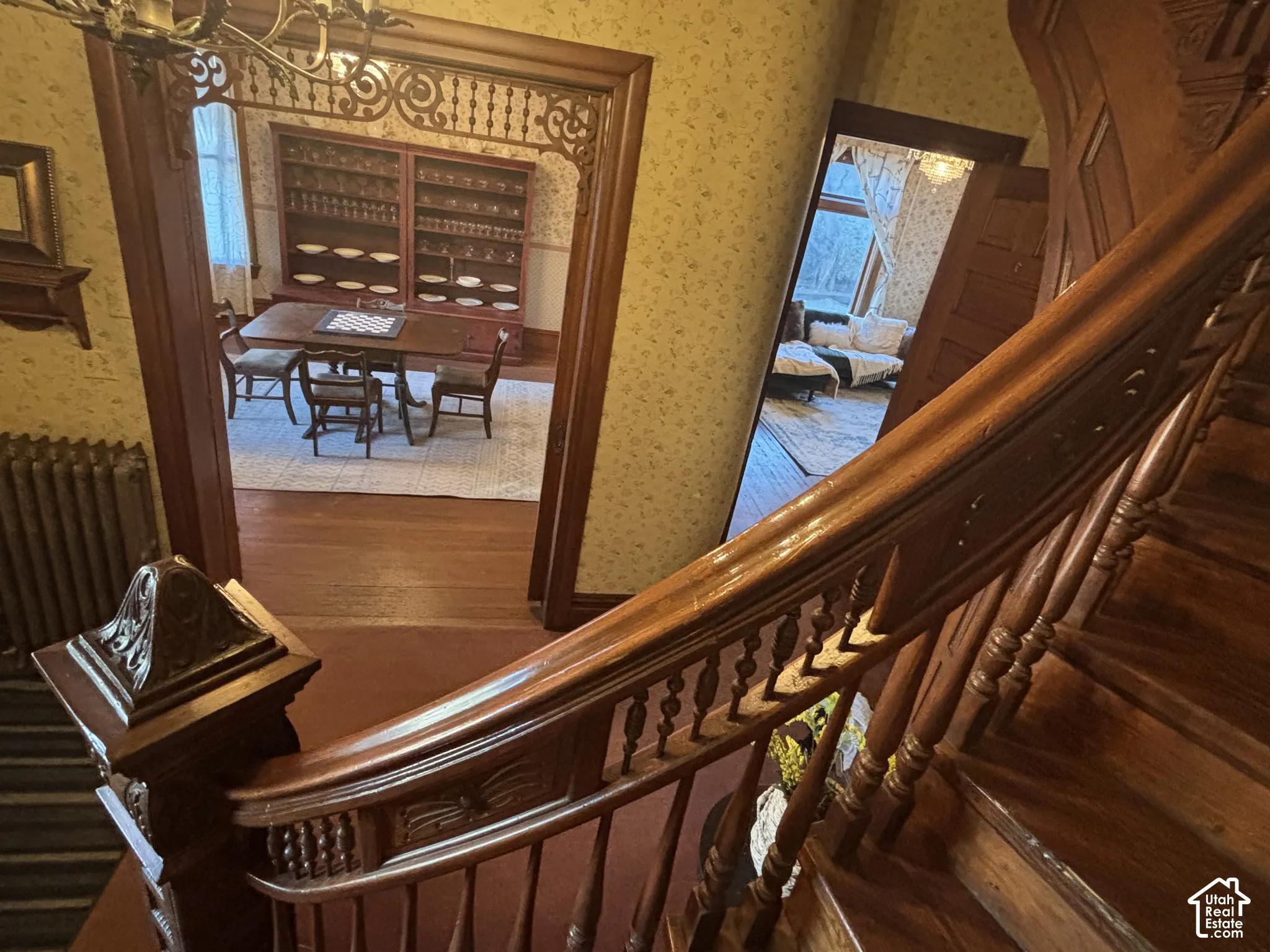 Staircase featuring a carved wood banister, decorative newel post, and spindle balusters, paired with arched doorway millwork and intricate wood fretwork detailing