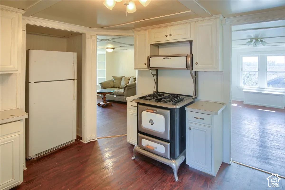 Kitchen with wood-finish flooring, built-in white cabinetry, integrated vintage-style range, and refrigerator alcove
