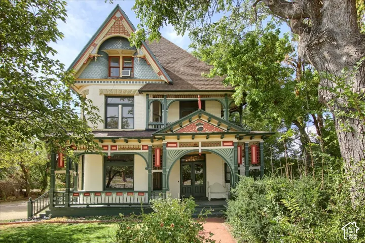 Victorian architectural style with intricate gingerbread trim, a prominent gabled roof, a welcoming covered front porch, and a brick pathway