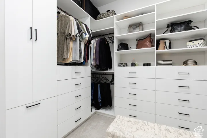 Custom built-in storage system featuring floor-to-ceiling cabinetry, adjustable open shelving, multiple soft-close drawers, matte black hardware, and integrated hanging rods