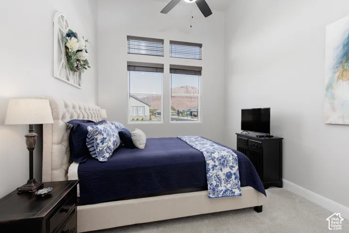 High-ceiling room featuring neutral carpeting, a ceiling fan with integrated lighting, and tall dual-pane windows with horizontal blinds