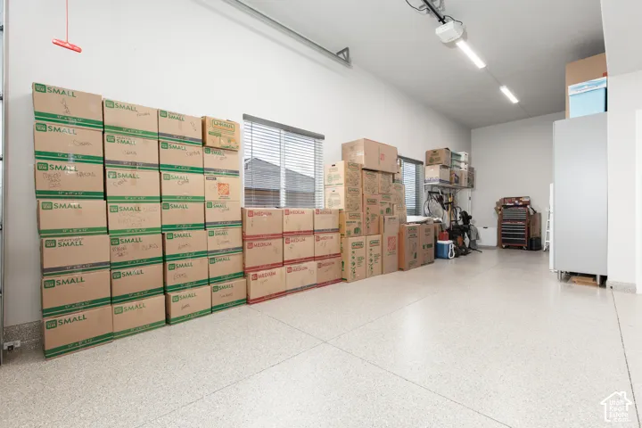 Garage interior featuring finished epoxy flooring, high ceilings, linear LED lighting, and window with horizontal blinds