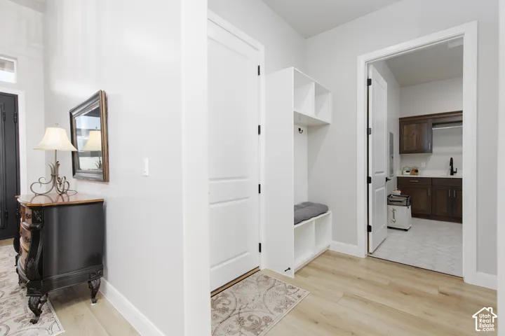 Entryway featuring wood-finish flooring, a white built-in mudroom bench with overhead storage, and recessed interior doors