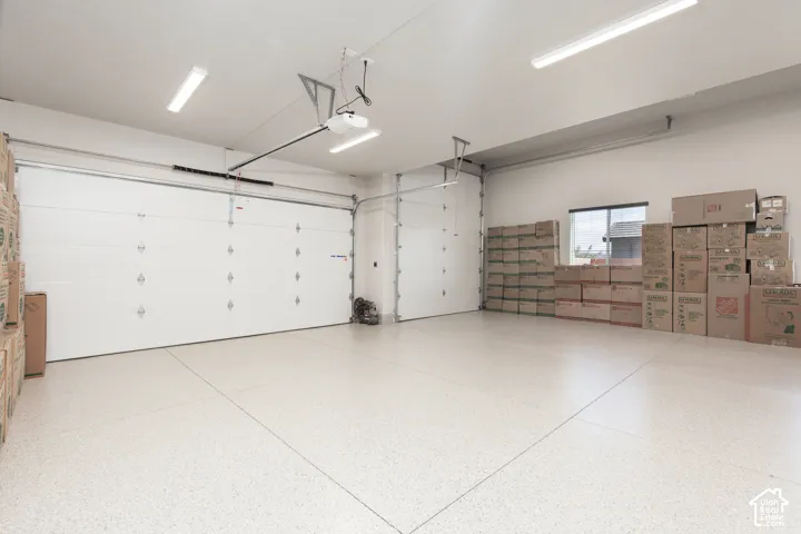 Attached garage featuring a dual-bay layout, high-gloss epoxy flooring, neutral wall finish, and overhead LED lighting