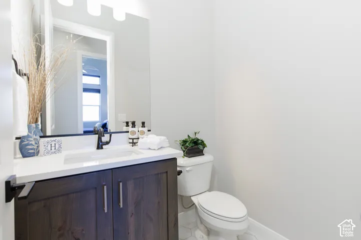 Dark wood-finish vanity with a white countertop, integrated rectangular sink, matte black faucet, and white hexagonal tile flooring