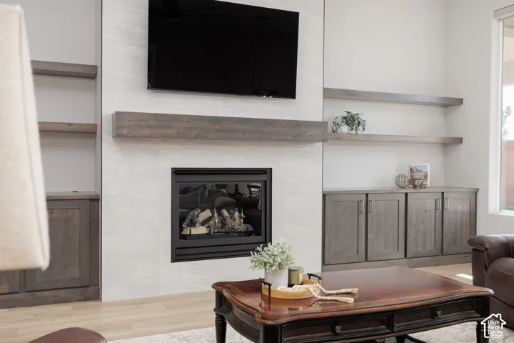 Fireplace with floor-to-ceiling tile surround, stained wood mantel, custom built-in cabinetry, and integrated open shelving