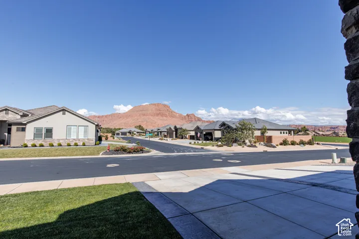 Concrete driveway, manicured lawn, and natural red rock mountain landscape