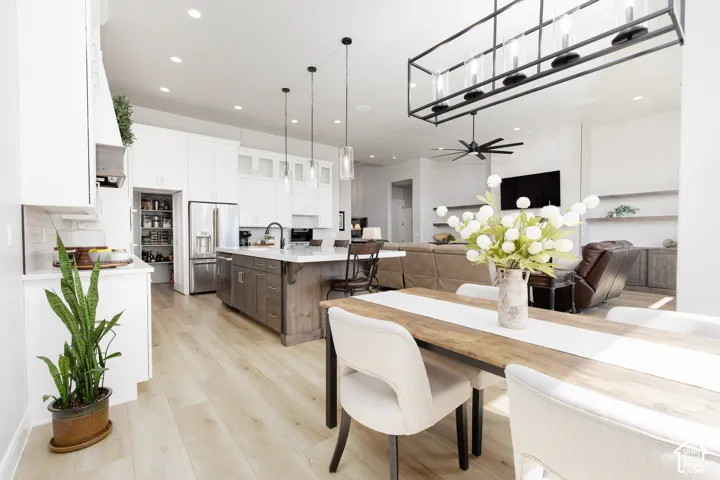 Kitchen featuring white shaker-style cabinetry, wood-finish flooring, central island with seating space, walk-in pantry, and linear matte black pendant lighting