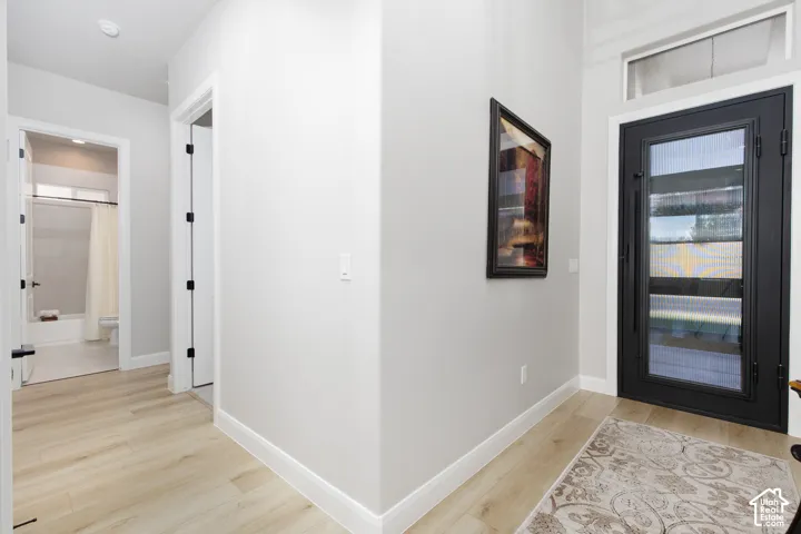 Entryway featuring light-toned wood-finish flooring, a black-framed glass-paneled door, and a horizontal transom window