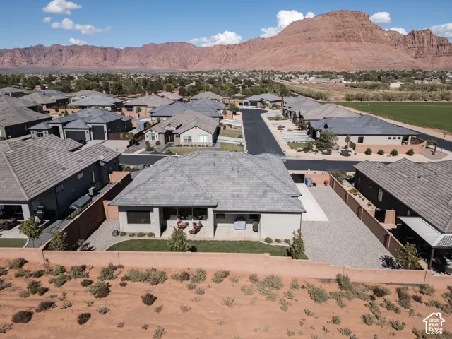 Exterior of a single-story residence featuring a tile roof, a covered concrete patio, a partially fenced perimeter wall, and proximity to mountain terrain