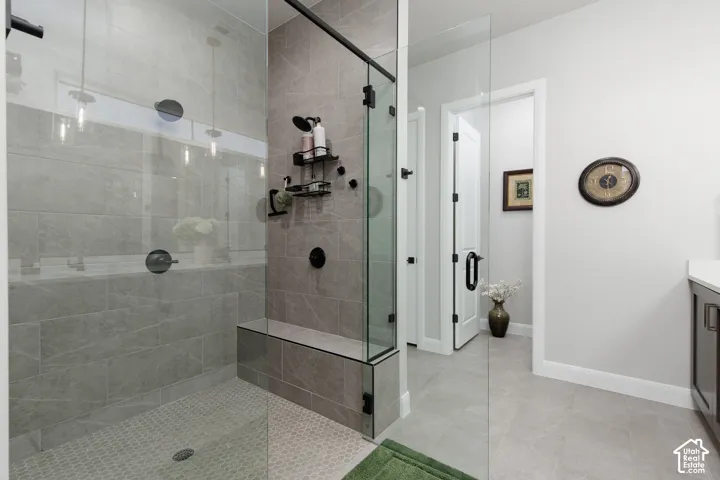Walk-in shower featuring large-format tile walls, integrated tiled bench seating, glass enclosure, and matte black fixtures