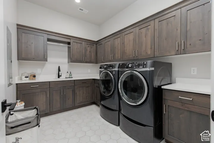 Laundry room featuring stained wood cabinetry, quartz countertops, a drop-in sink with a matte black faucet, and hexagonal tile flooring