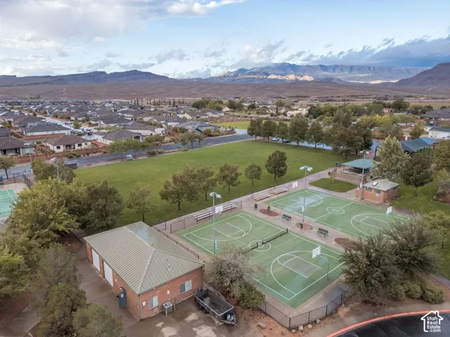 Community recreation area featuring multiple sports courts, a brick-facade pavilion, expansive lawn space, and mountain backdrop
