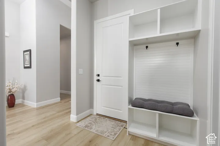 Built-in white mudroom cabinetry with beadboard paneling, integrated storage shelving, and matte black hardware, accompanied by light wood-finish flooring