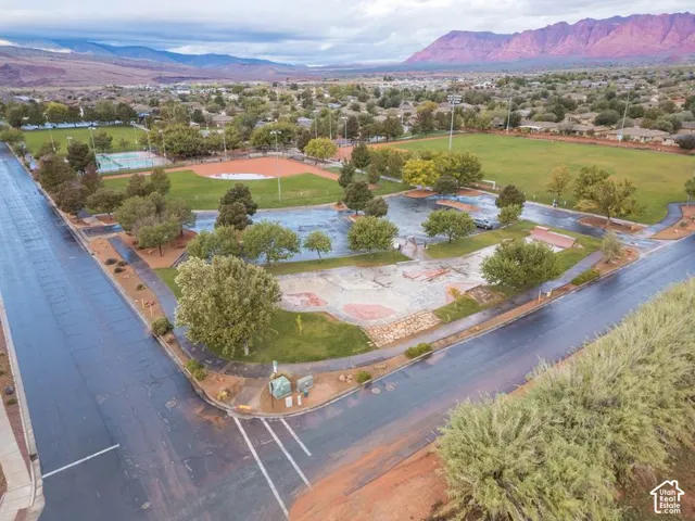 Aerial perspective featuring expansive park grounds, concrete skate park infrastructure, baseball diamond, open multi-use turf fields, and prominent mountain backdrop