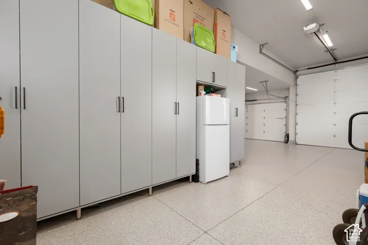 Garage featuring custom wall-to-wall cabinetry, epoxy-finished flooring, and two separate overhead garage doors