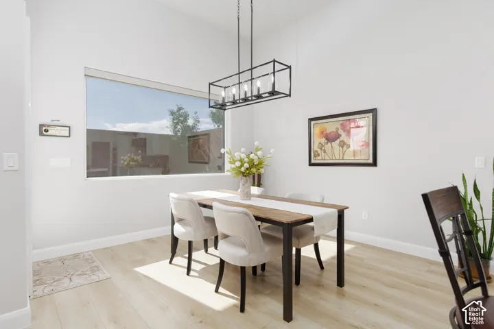 High-ceiling room featuring wood-finish flooring, a rectangular picture window, and a matte black linear pendant light fixture