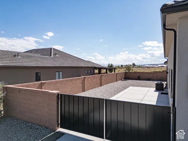 Rear yard featuring a concrete patio, gravel landscaping, a tan masonry wall, and a black metal gate