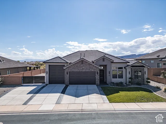Single-story exterior featuring a stone veneer facade, tile roof, three-car garage, and concrete driveway