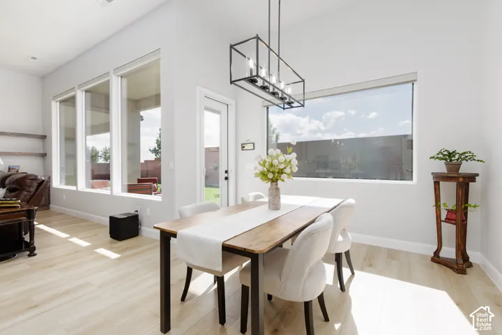 Dining area featuring high ceilings, wood-finish flooring, oversized windows, and a black metal geometric pendant light