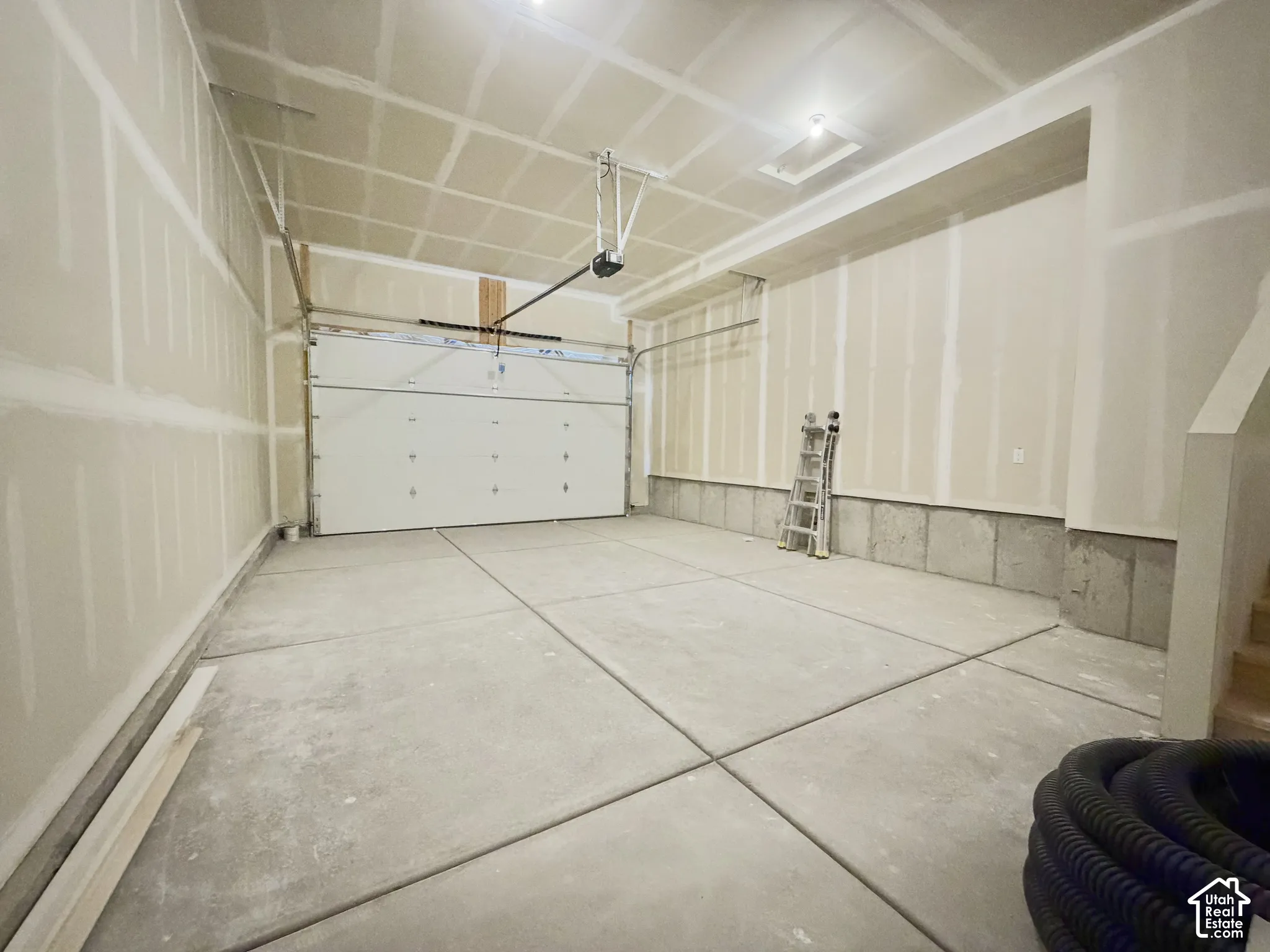 Spacious multi-car garage with concrete flooring, finished drywall, and an automated overhead door mechanism