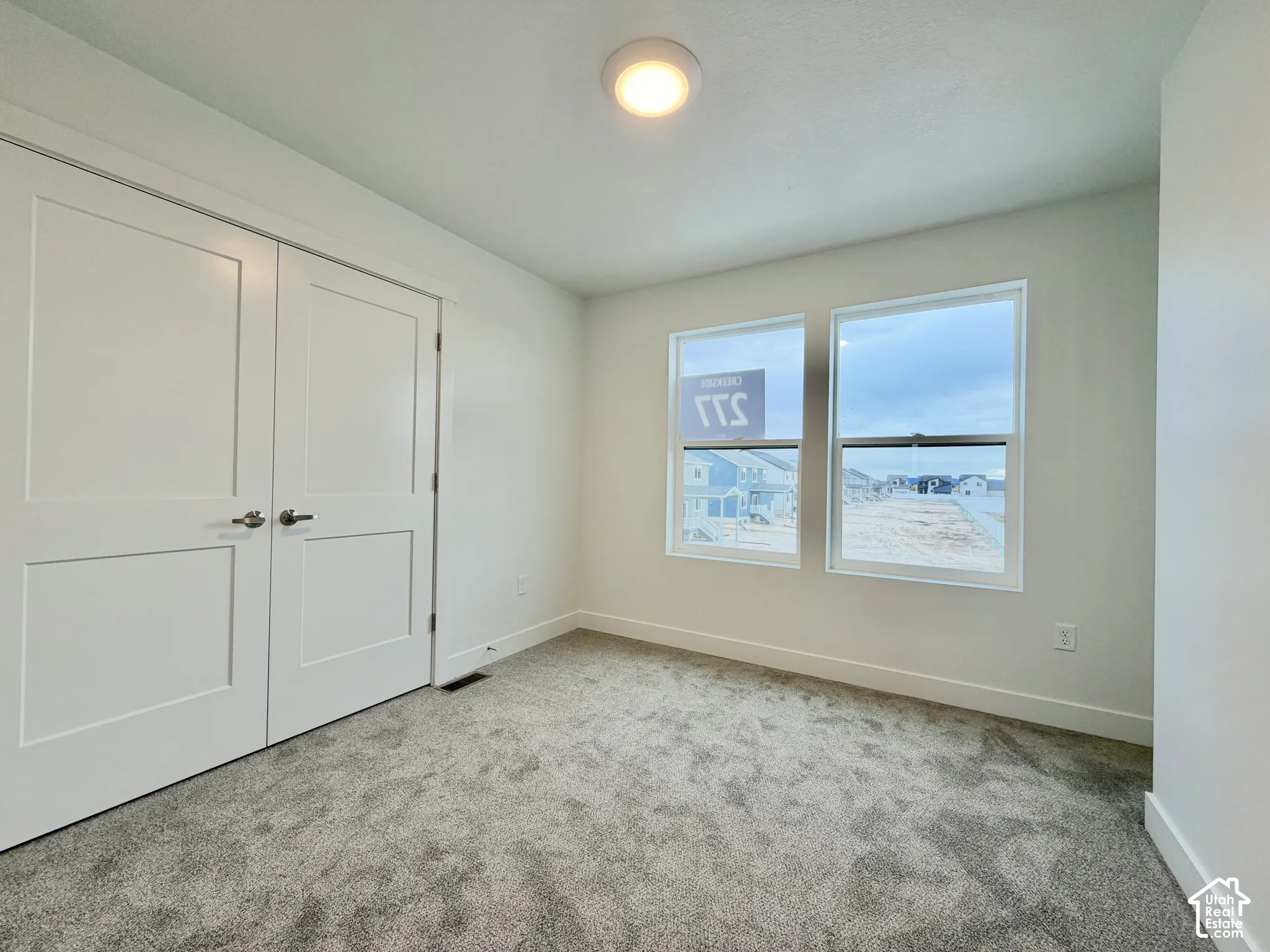 Neutral interior space featuring carpeted flooring, two double-panel doors, and dual windows with silver hardware