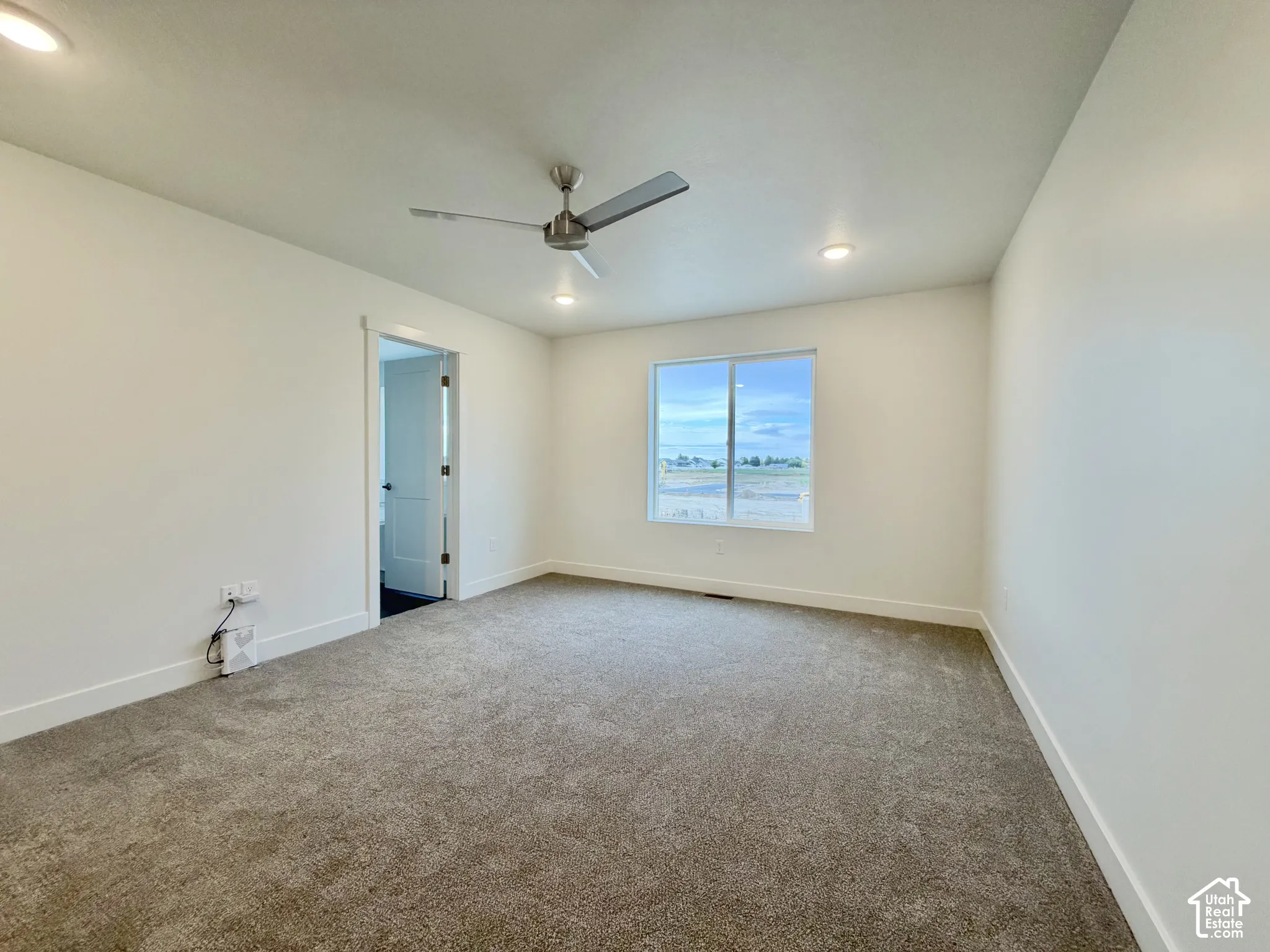 Neutral-toned carpeting, recessed ceiling lighting, brushed metal ceiling fan, and large picture window