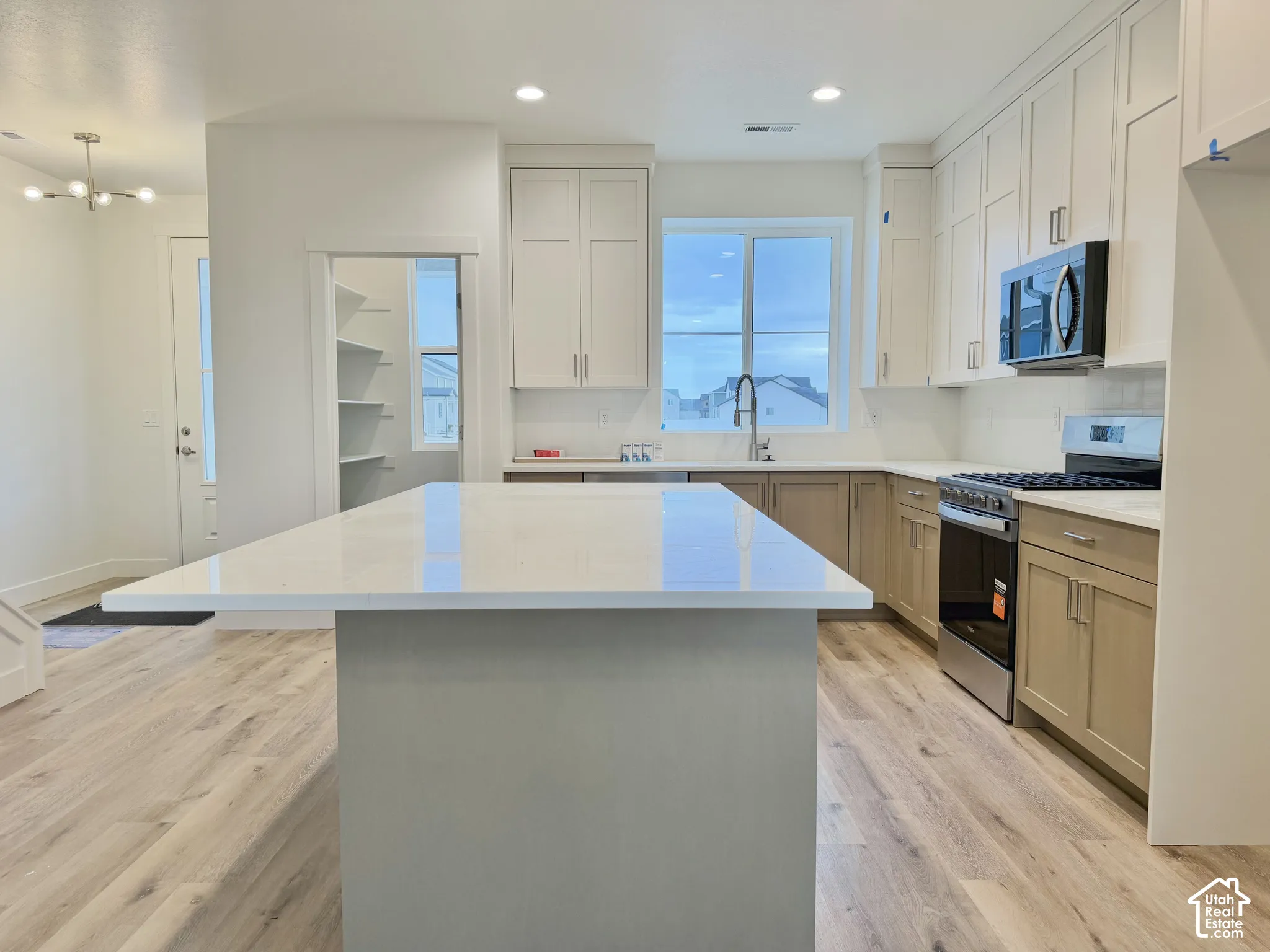 Kitchen featuring a spacious island with a white stone countertop, two-tone shaker-style cabinetry, recessed ceiling lighting, and wood-finish flooring