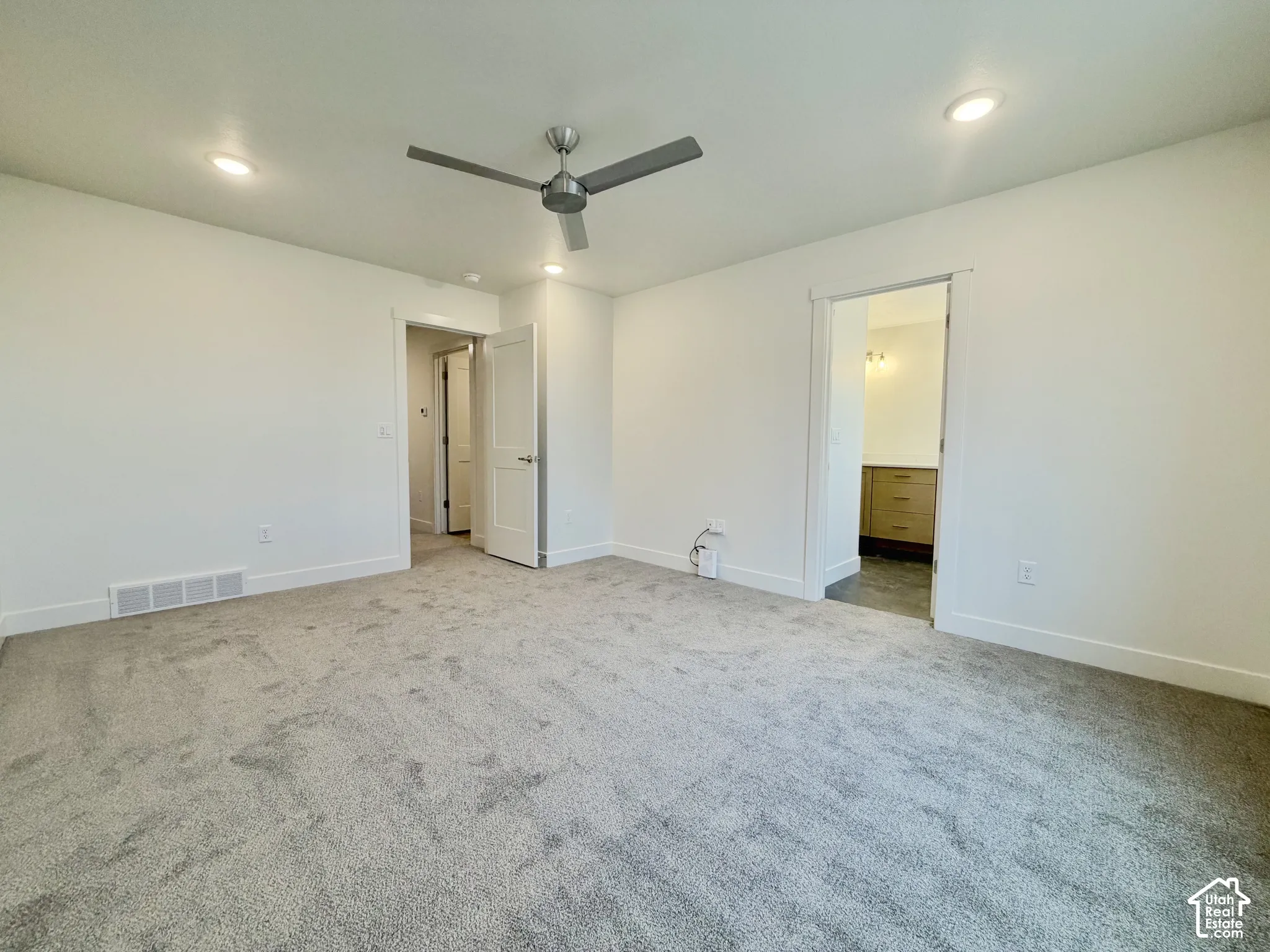 Neutral-toned carpeting, ceiling-mounted paddle fan, recessed lighting, and solid-core doors