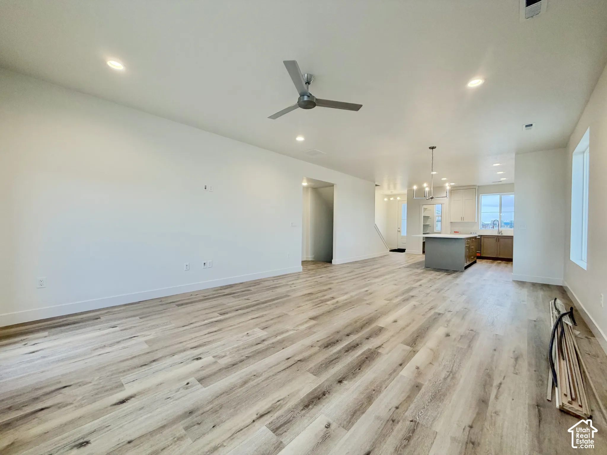 Open-concept interior featuring wood-finish flooring, recessed lighting, a modern ceiling fan, and a kitchen island with cabinetry