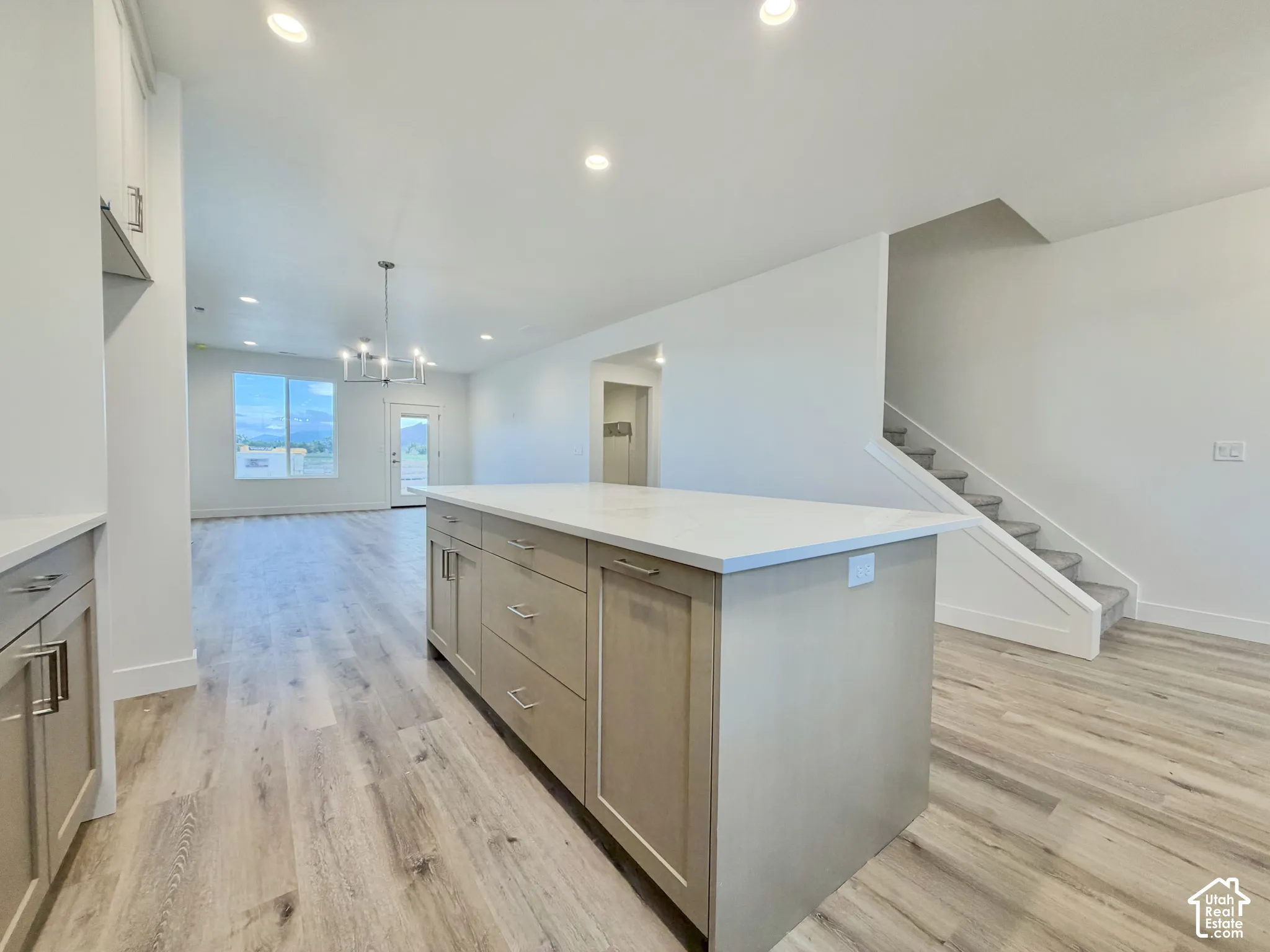 Kitchen island featuring light-toned cabinetry and a white countertop, wood-finish flooring, recessed lighting, and a chandelier