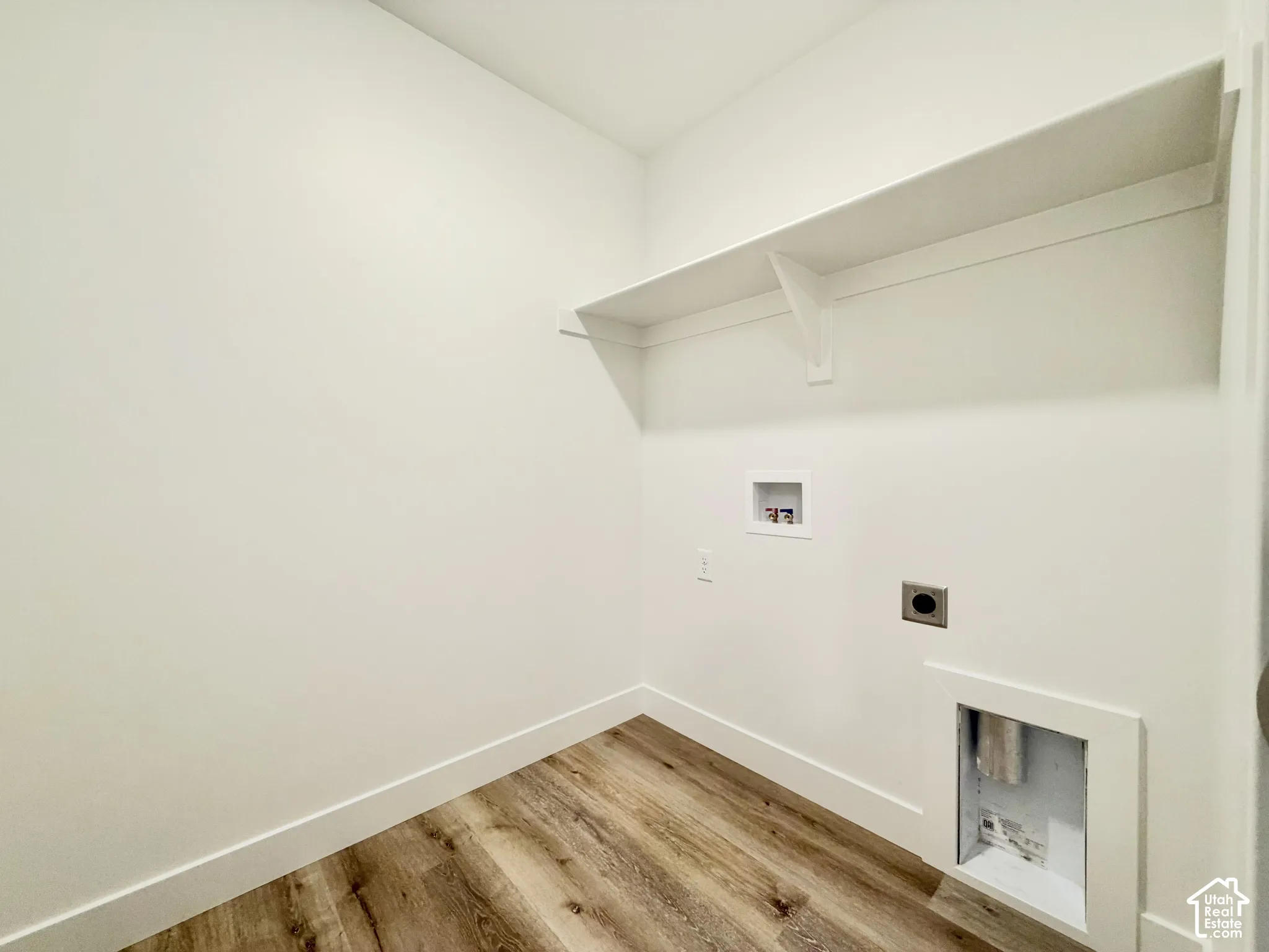 Utility space featuring wood-finish flooring, white walls, and built-in shelving