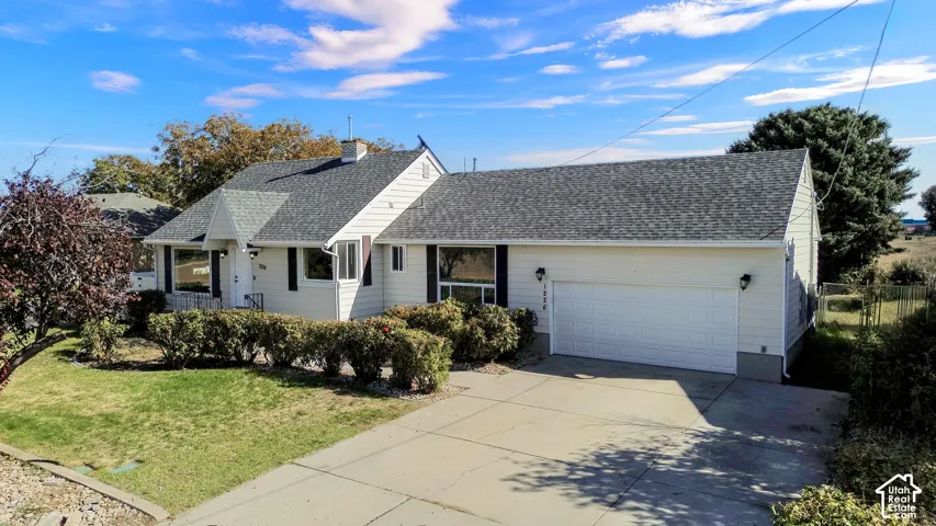 Single-story exterior featuring light-colored horizontal siding, a pitched shingle roof, a two-car garage, and a concrete driveway