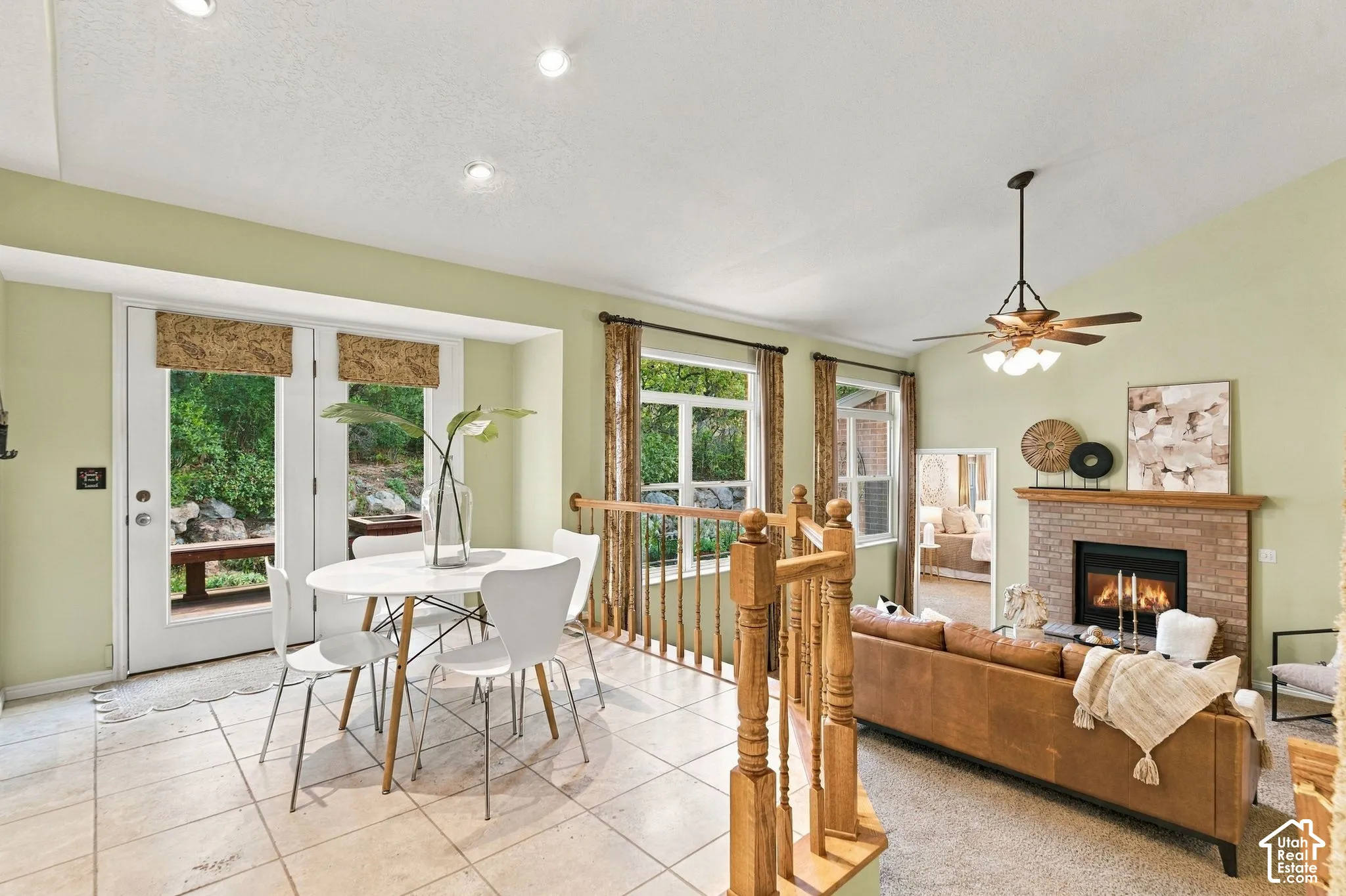 Vaulted ceilings, tile flooring, brick-surround fireplace, wooden balustrade, and recessed lighting