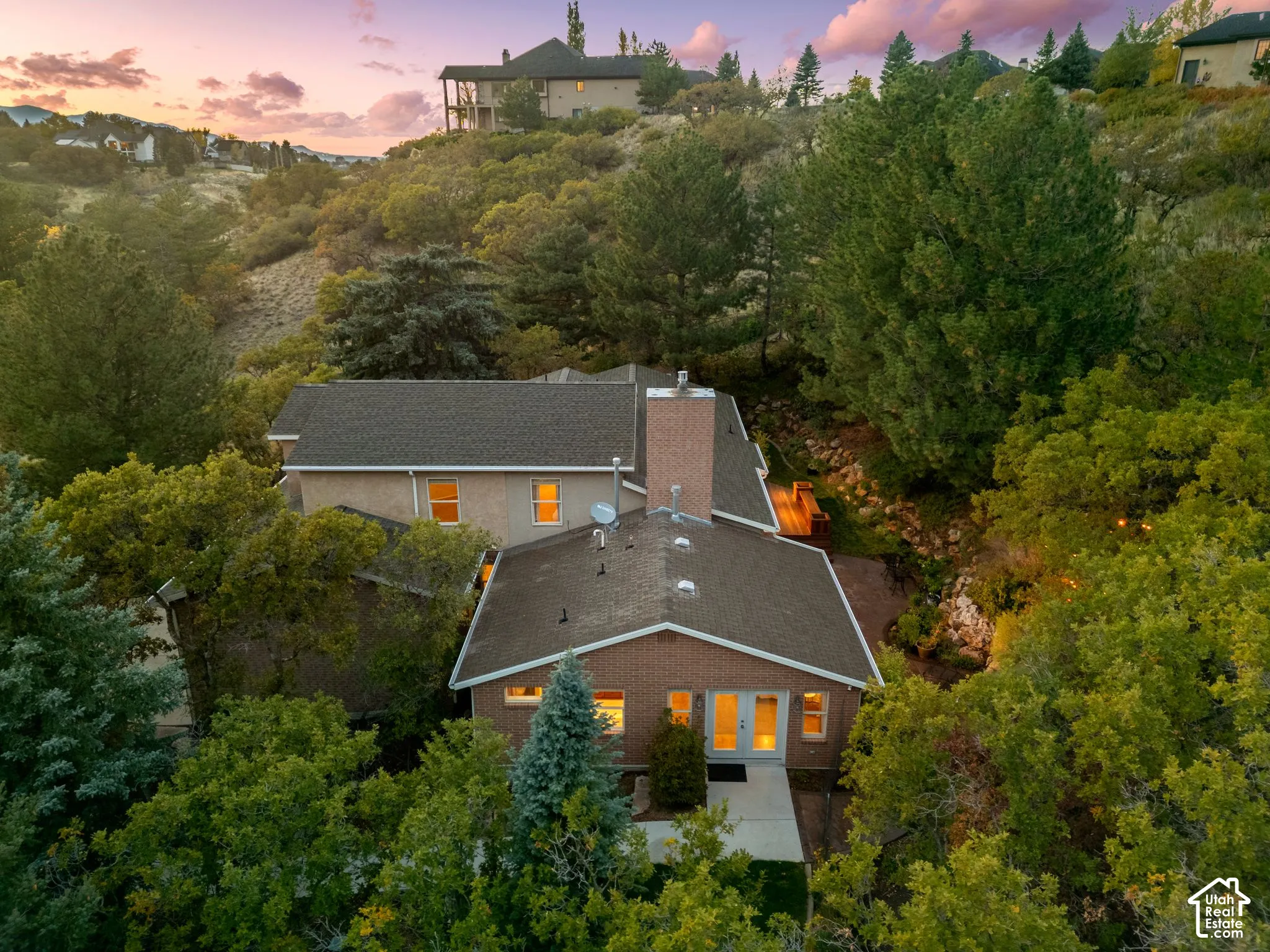 Multi-level residence featuring a brick and stucco exterior, tall masonry chimney, dual-material roofline, and glass-paned double doors
