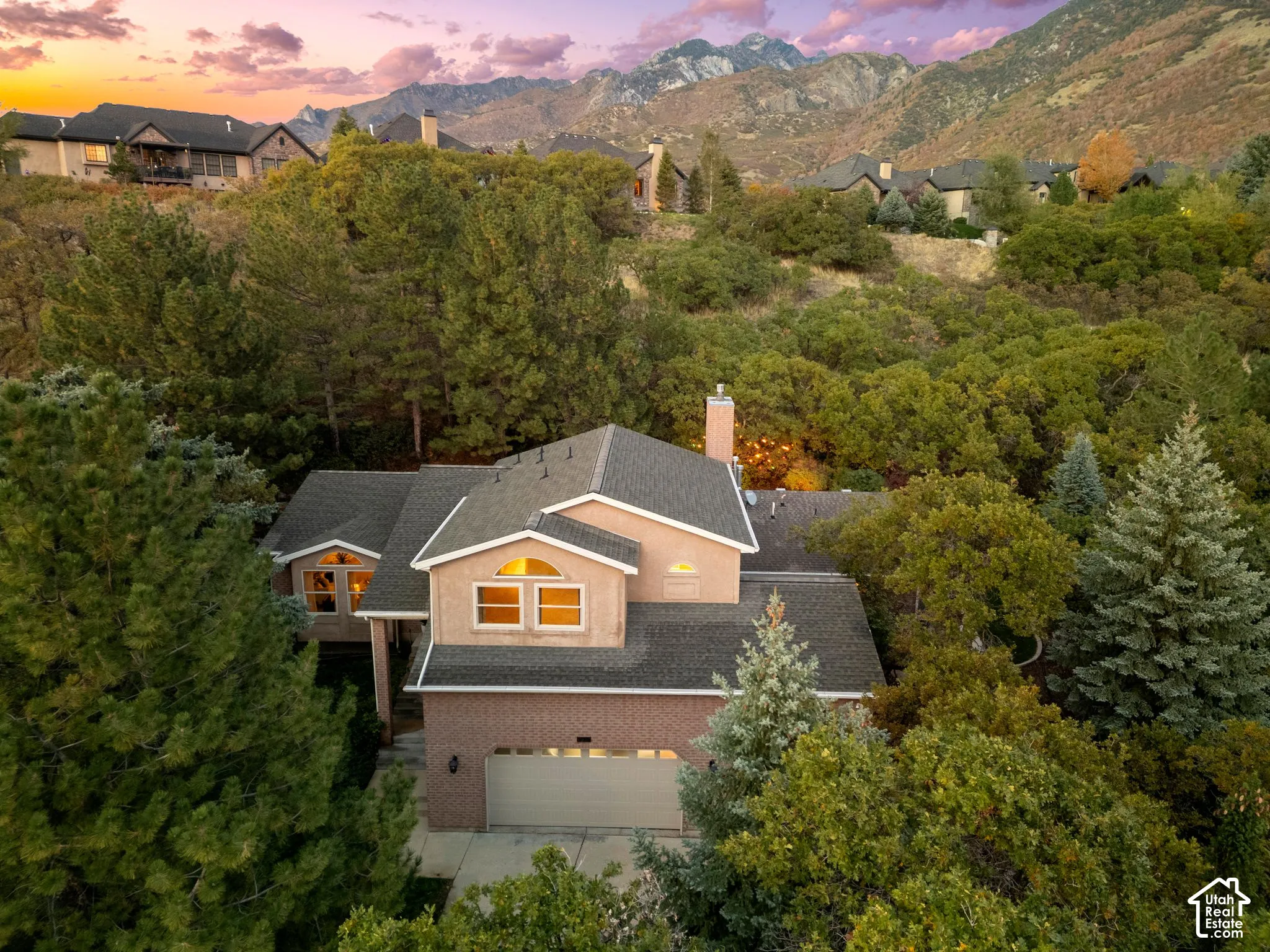Multi-level residence featuring a brick and stucco exterior, an attached garage, a chimney, and expansive mountain scenery