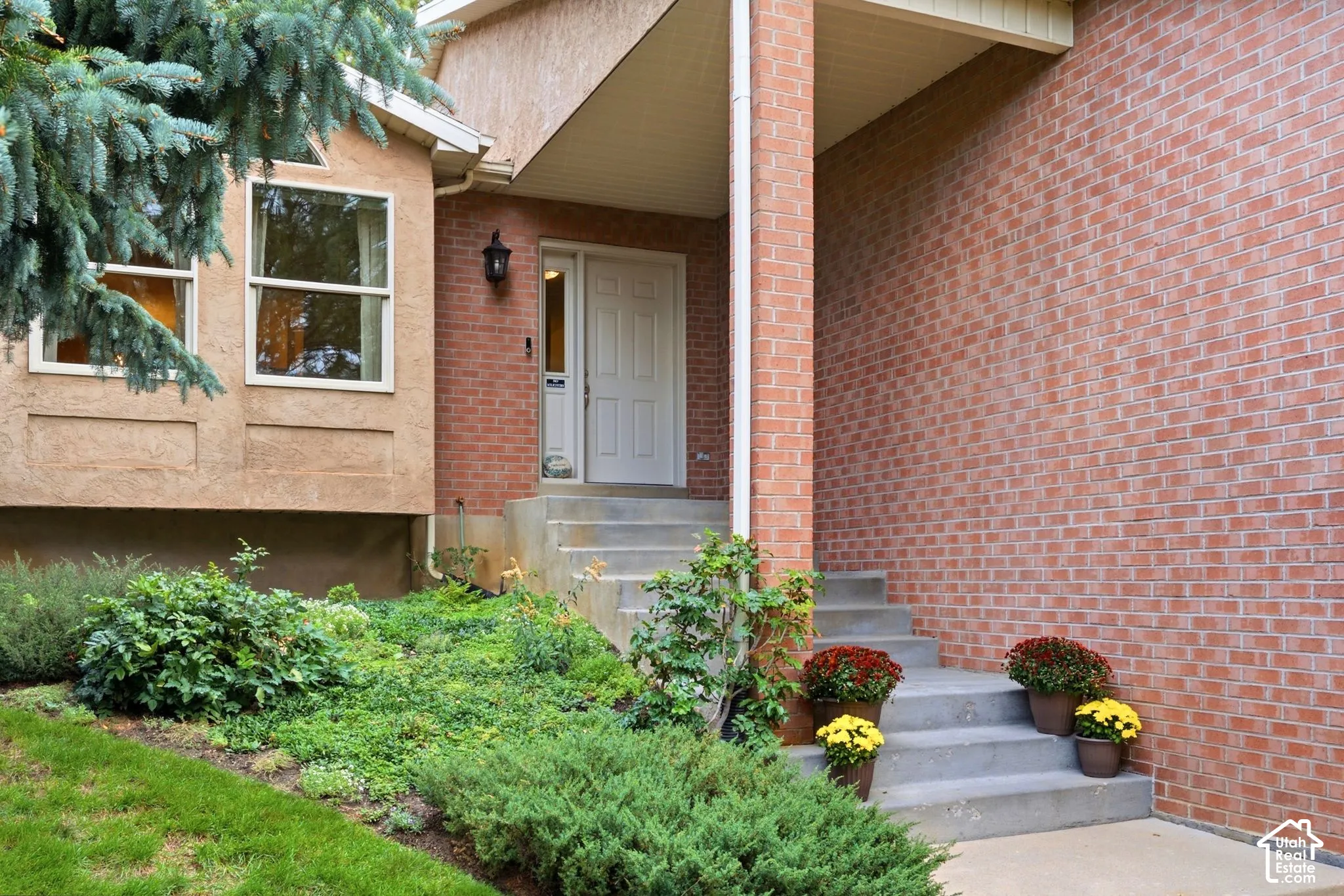 Exterior entry featuring red brick siding, a concrete staircase, and a paneled front door with a side light