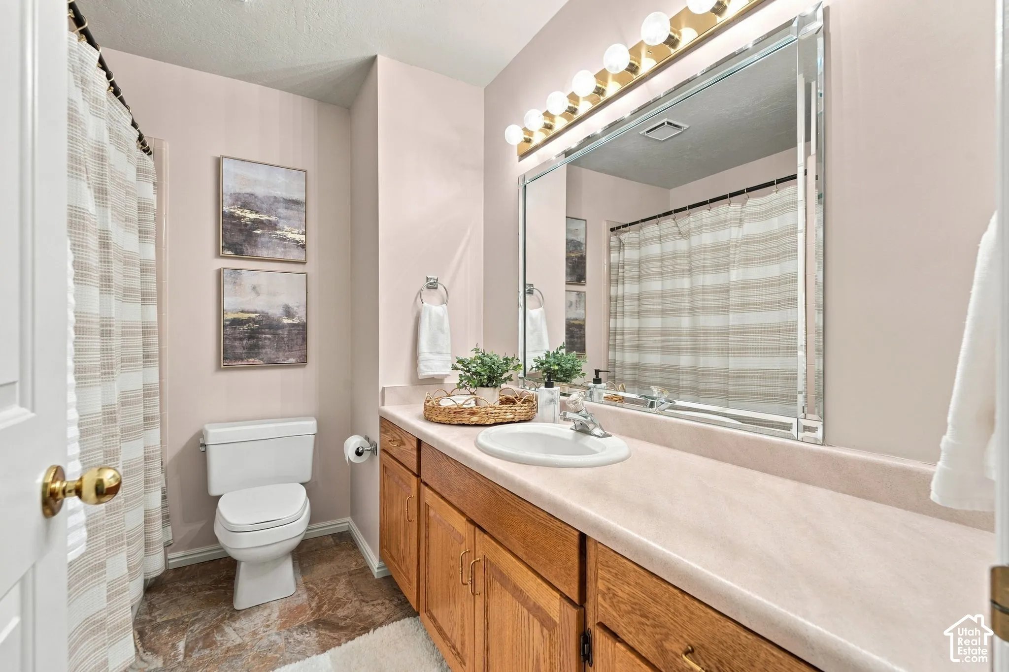 Full-width vanity with integrated countertop and sink, wooden cabinetry, large beveled-edge mirror, and multi-bulb light fixture
