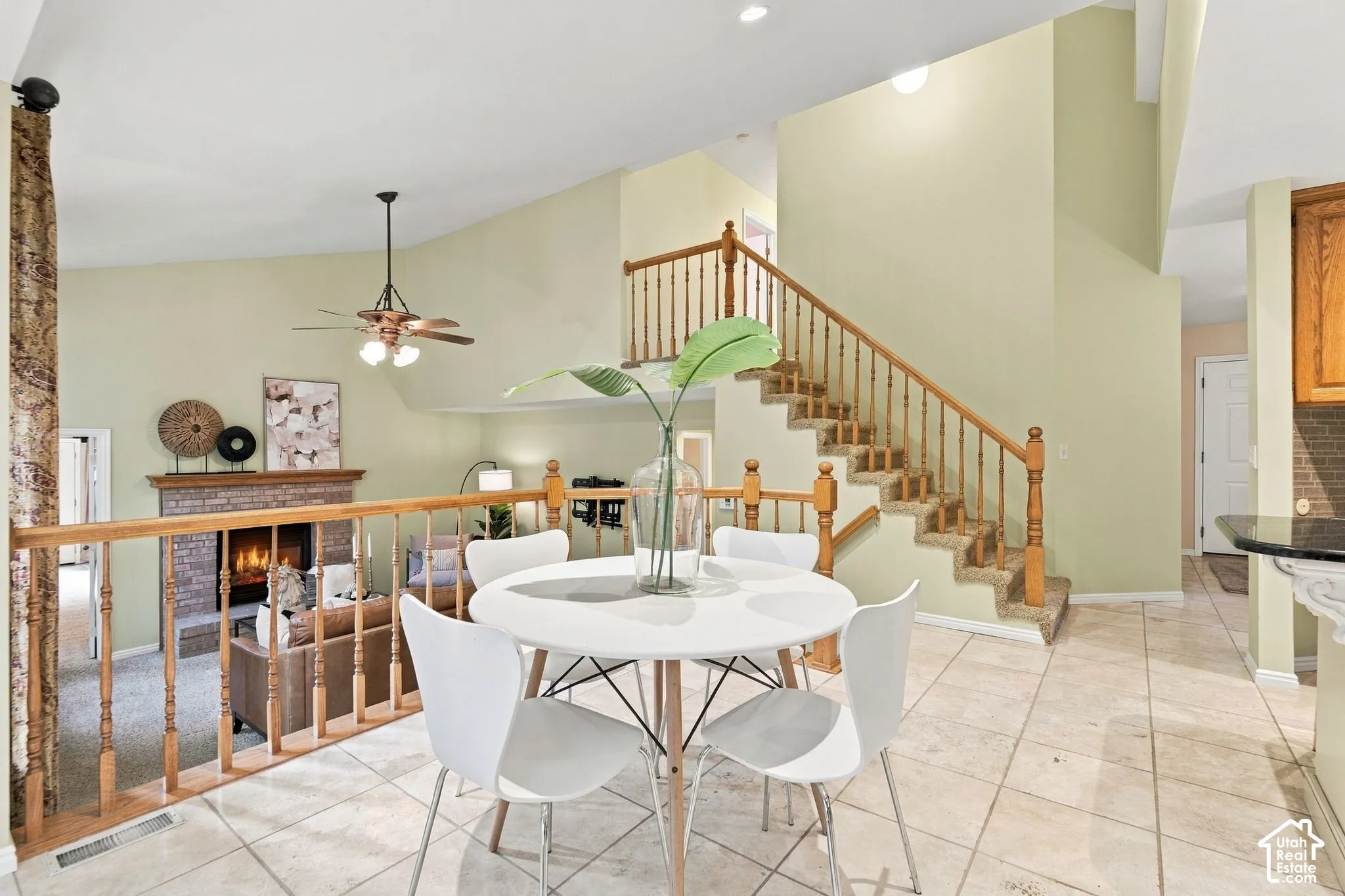 Vaulted ceilings, staircase with wooden balusters, stone-finish fireplace, and tile flooring