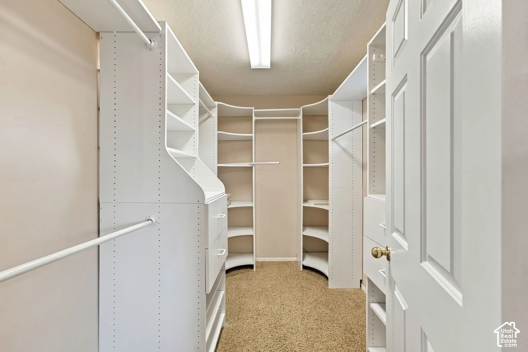 Second Floor Primary Suite Walk-in closet featuring white built-in shelving, integrated storage drawers, wall-mounted garment rods, and overhead linear lighting